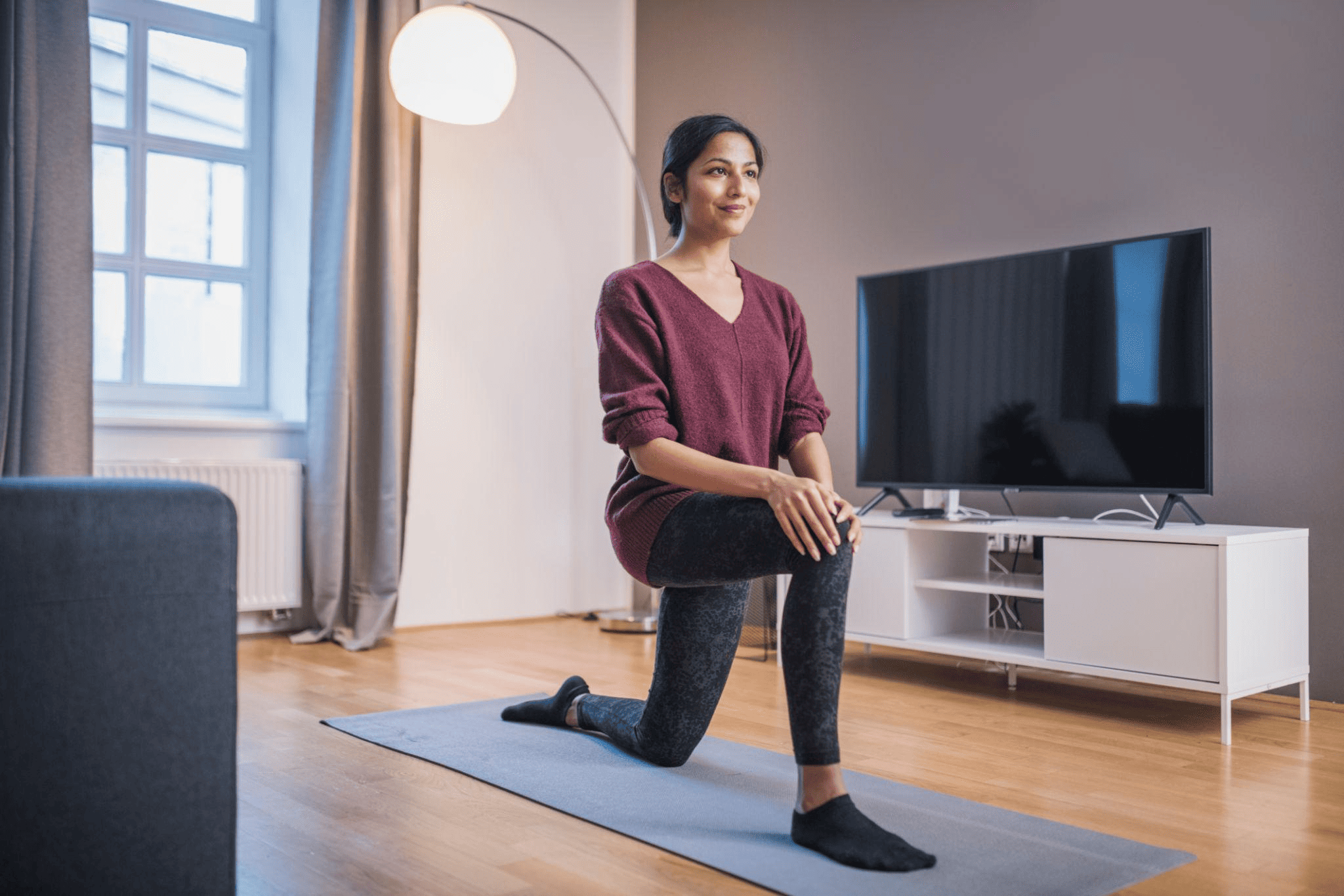 woman in her house doing yoga and applying jc best pain relief oil