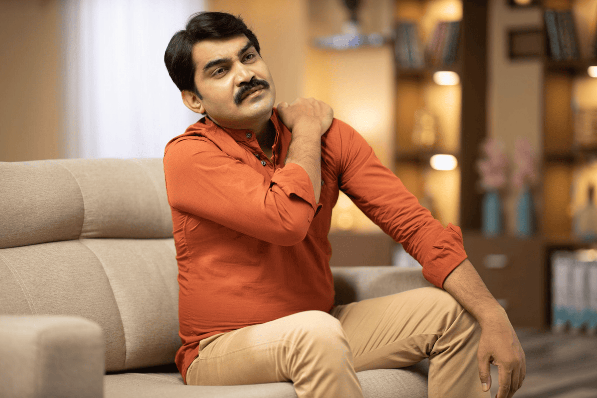 Indian man experiencing muscle and shoulder pain while looking for muscle pain relief oil